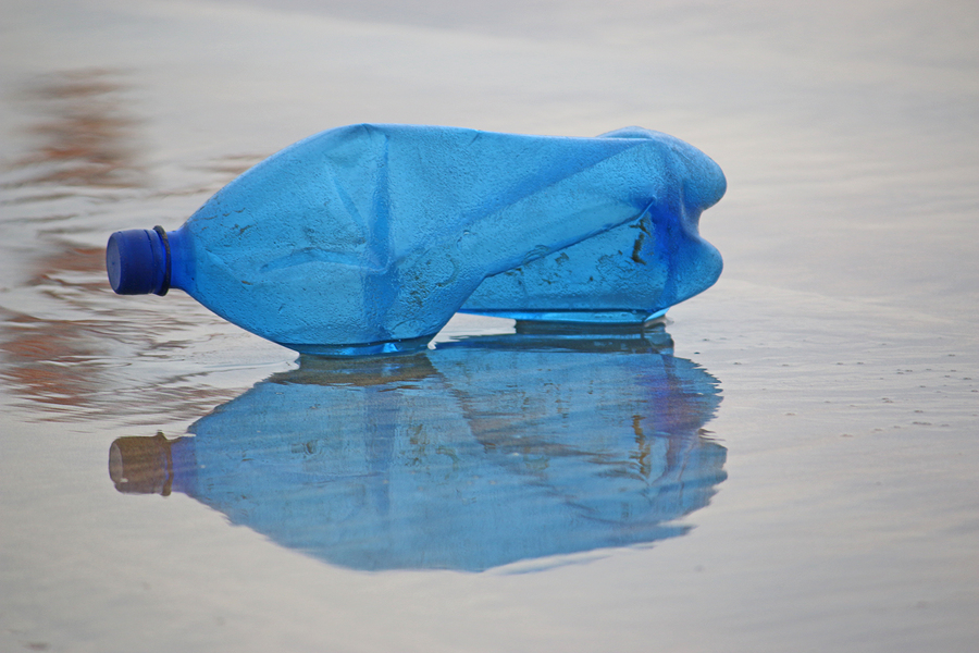 Blue plastic bottle reflected on a beach