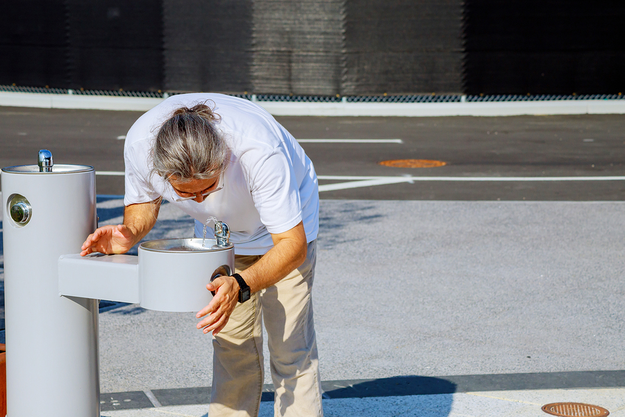 Man drinking water from drinking fountain in park at street a water