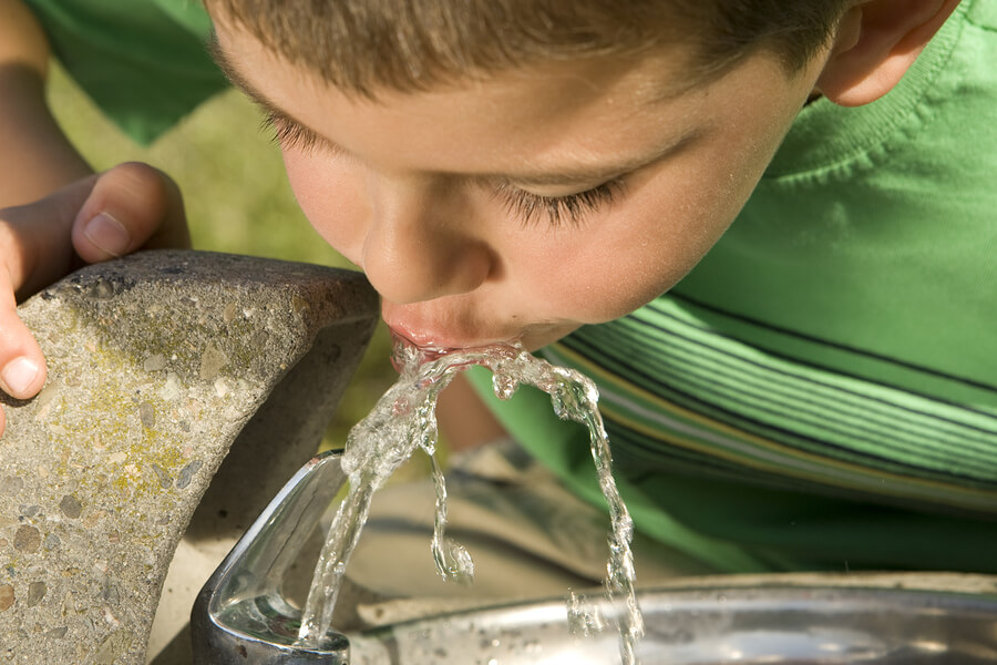 A picture of a little boy drinking from a water fountain.