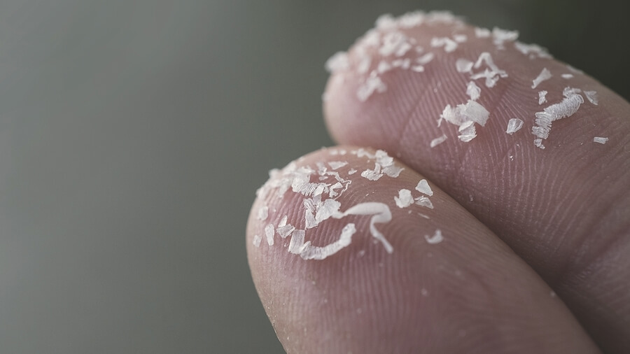 Close up side shot of microplastics on human fingers. Concept for water pollution and global warming.