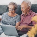 An old couple check their bills using a laptop