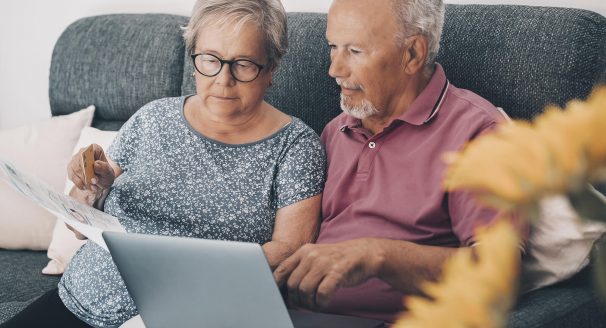 An old couple check their bills using a laptop