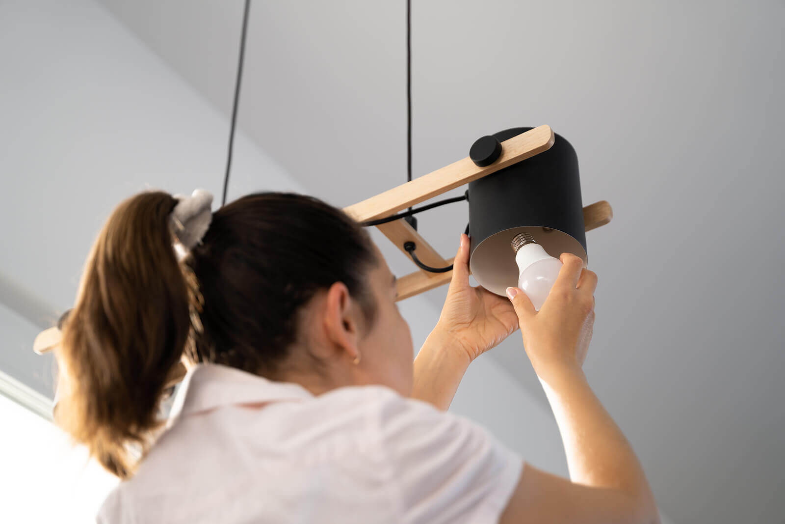 A lady installs an LED lightbulb.