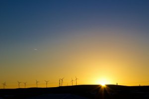 Sunsetting over scenic hill with wind turbines in the forefront