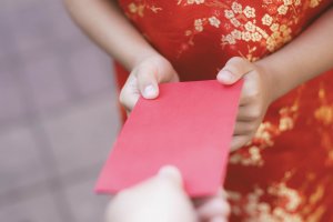  Chinese Lunar New Year celebrations. Red envelope (ang pao) being given to a child.