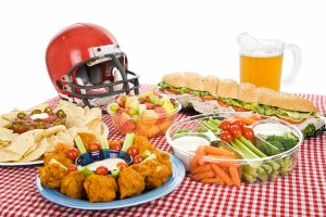 An array of Super Bowl party food laid out on a table with a red and white chequered tablecloth.